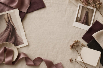 Fabric swatches, a Polaroid of a gown and a blank note card laid out on ivory linen