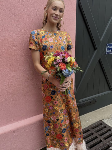 Rent with Rêve customer in a rust floral dress with a feather hem, holding a bouquet